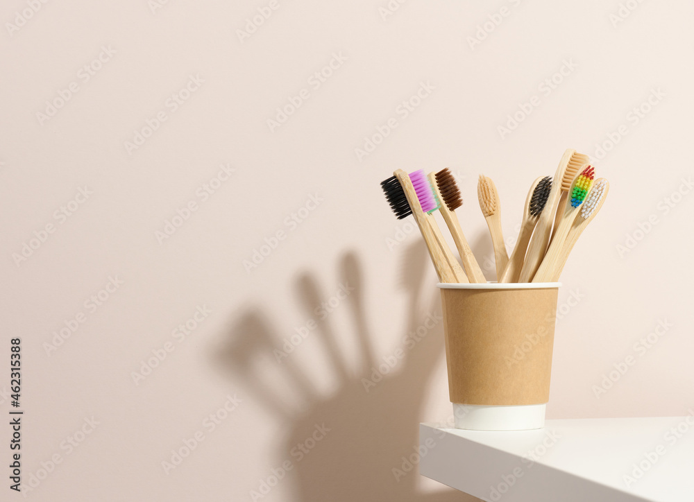 wooden toothbrushes in a paper cup on a white table. Beige background, zero waste wooden toothbrushes in a paper cup on a white table. Beige background, zero waste