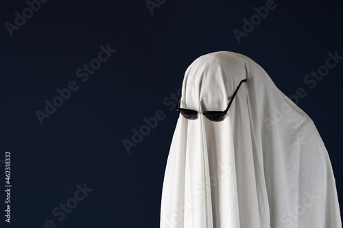 Sad person in Halloween costume of ghost with sunglasses photo