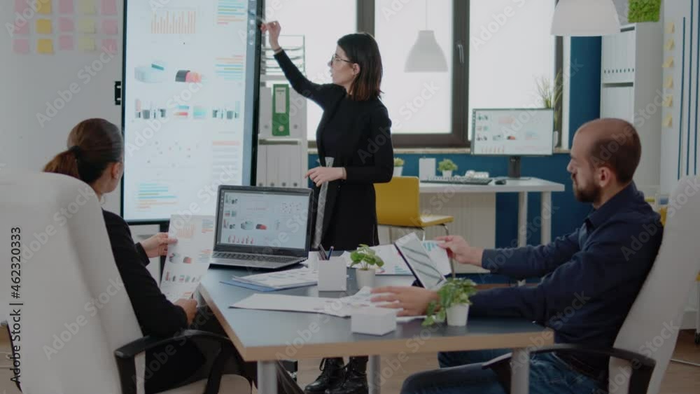 Colleagues looking at presentation on television with data charts for ...