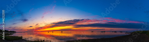 Panoramic view of a beautiful sunset sky over the sea with boats in Loissin bei Greifswald photo