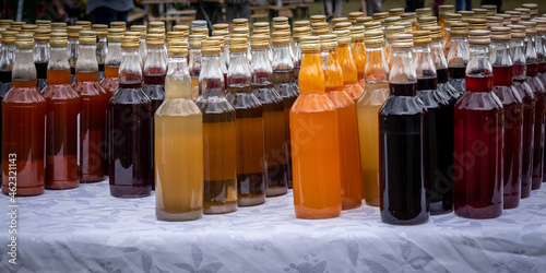 Rows of bottles of homemade alkohol tincture, standing outdoors on the table.  photo