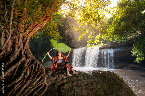 girl sitting on the rocks Use leaves to cover the waterfall. with a waterfall in the background