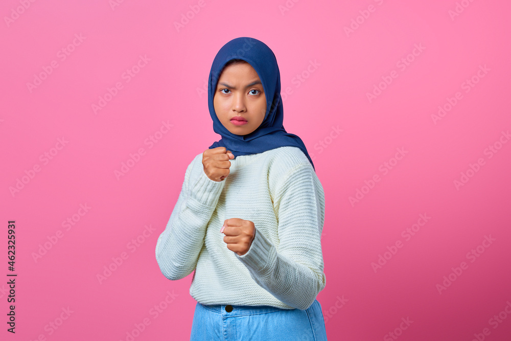 Portrait of angry young Asian woman showing boxer gesture on pink background Portrait of angry young Asian woman showing boxer gesture on pink background