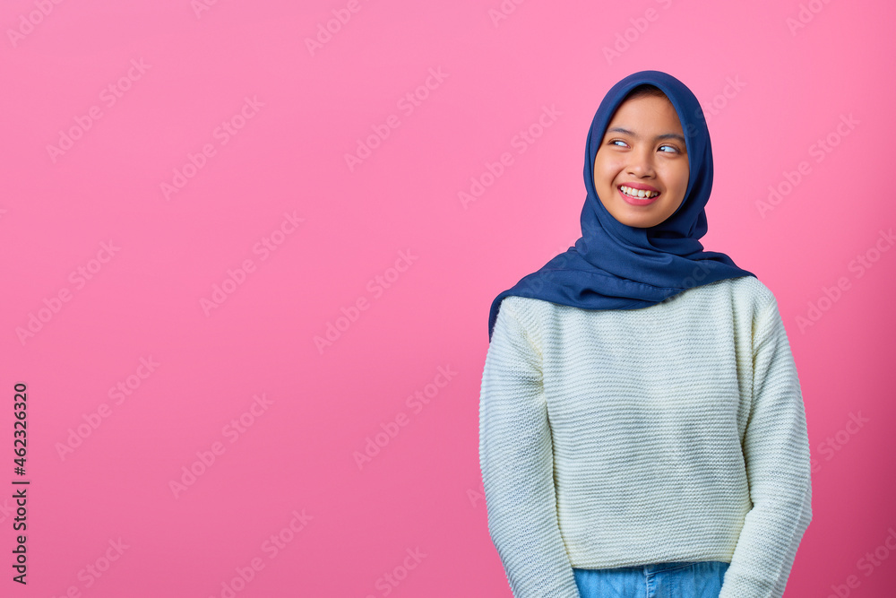 Portrait of smiling young Asian woman looking away to side on pink background Portrait of smiling young Asian woman looking away to side on pink background