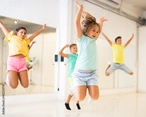 Group of positive kids jumping while dancing together in studion.