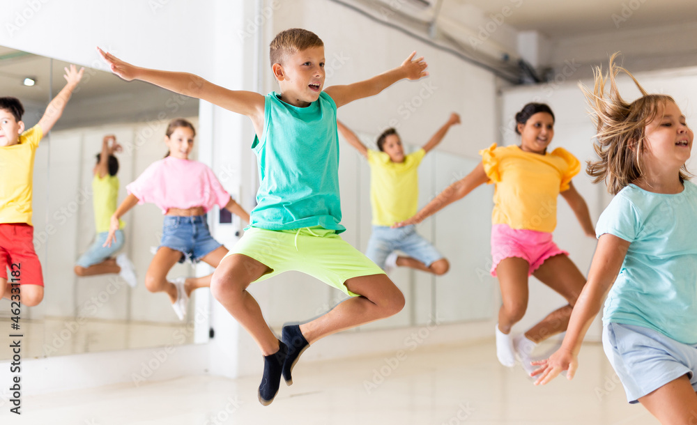 Young girls and boys jumping together in dance studio.