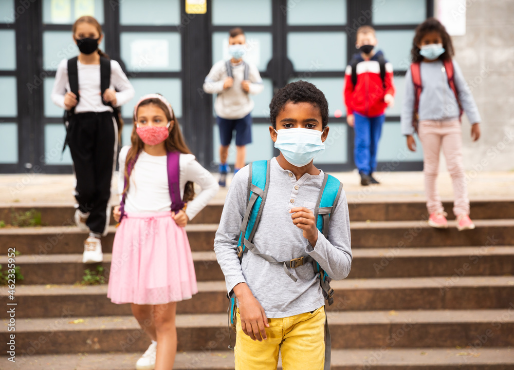 African american tween schoolboy in protective mask with backpacks going to school lessons on fall day. Back school concept during pandemic