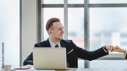Executive caucasian man smile and bump fist with colleague woman as happy for professional team agreement on amazing business solution and success to win corporate deal at conference room