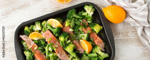 Foto baking sheet with salmon and broccoli on a light table