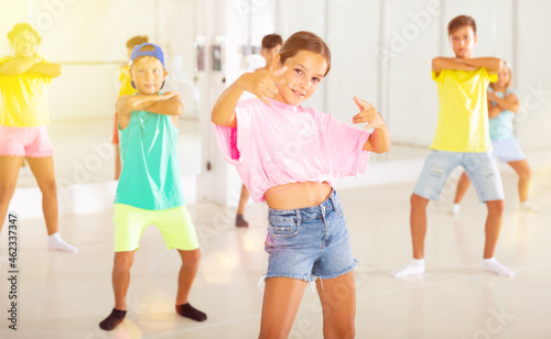 Portrait of modern tween girl krump dancer in choreographic studio with dancing children in background.