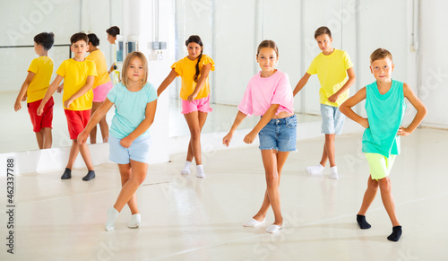 Happy tweens dancing together during group class in modern choreographic studio.