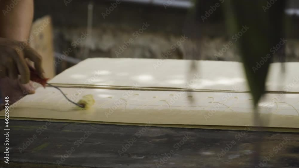 Paint roller distributing glue on wooden plank of skateboard in manufacture