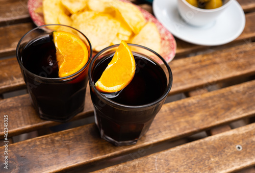 Vermouth with slice of orange and spanish tapas, olives and fried potatoes