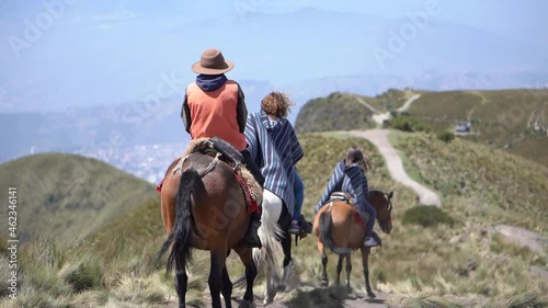 Tourists are riding horses on a trail of Rucu Pichincha near Quito Ecuador. They are wearing ponchos.