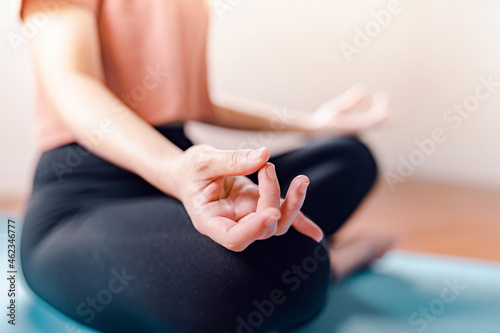 Close up - Woman practicing yoga lesson, breathing, relaxing, working out indoor at home. Well being, wellness concept.