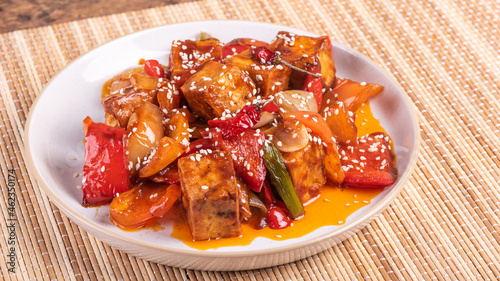 Stir fry tofu with onion and pepper in hot sauce on a plate - asian vegetarian cuisine