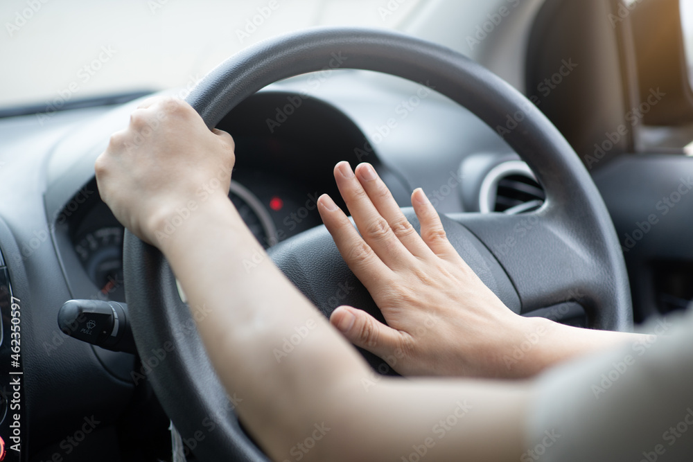 A woman honking a car horn loudly in a black car. riot concept and accidents.