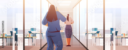 businesswomen couple standing back to camera rear view of business people in office corridor cartoon characters