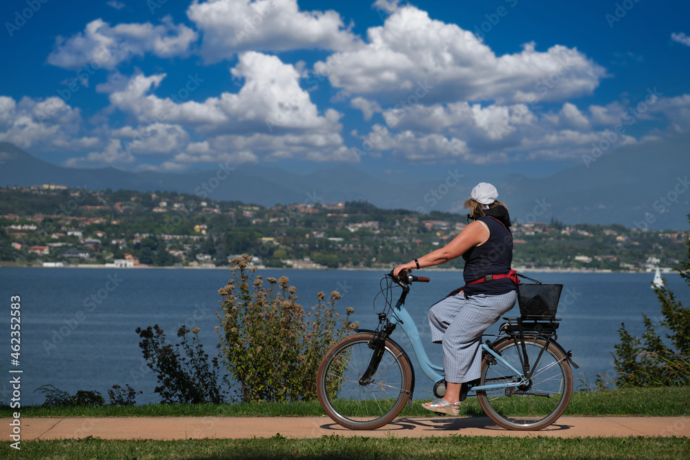 Woman on electric bike lake garda. Cycling along the lake in the Alps on an electric bike.