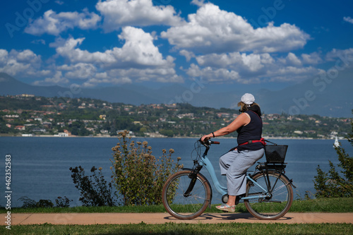 Woman on electric bike lake garda. Cycling along the lake in the Alps on an electric bike.
