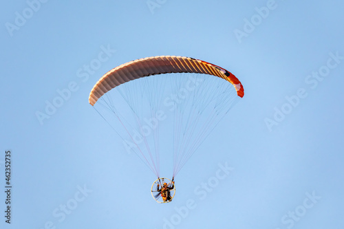 Powered paragliding flight against blue sky.