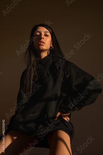 Foto portrait of a young woman with black oversize hoodie and defiant mood vertical c