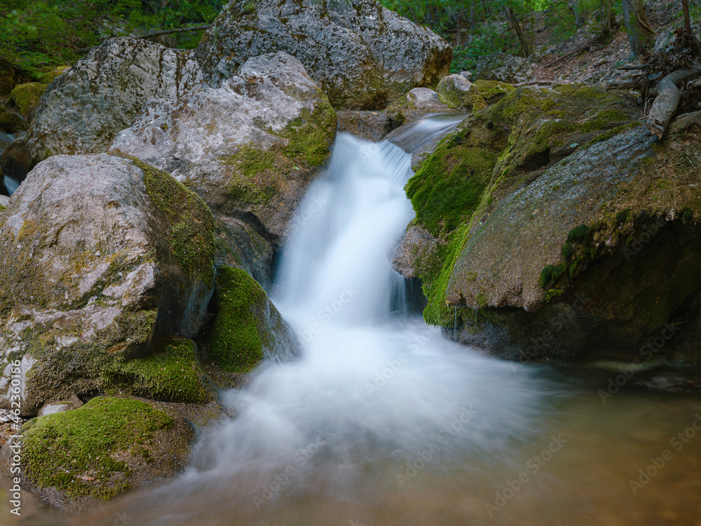 small river deep in the green woods. wonderful springtime scenery of mountains countryside. clear water among forest and rocky shore. wooden fence on the river bank.