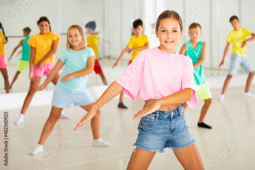 Positive girl exercising in group of classmates during dance class at school