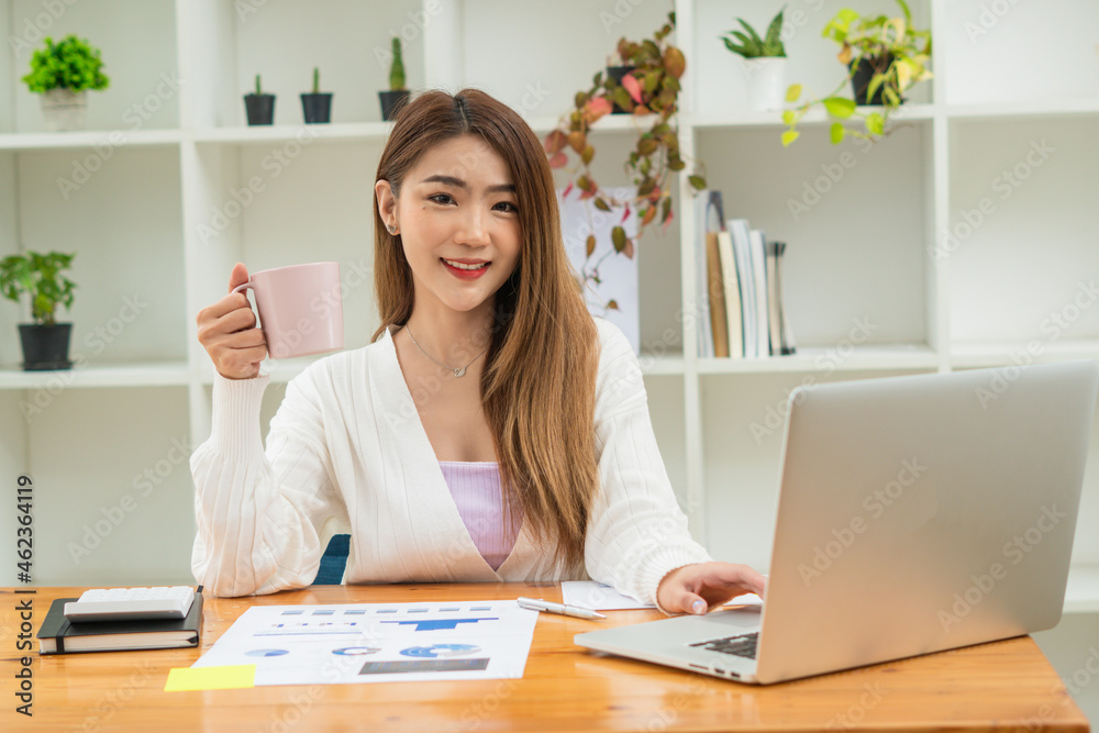 Happy young asian businesswoman sitting on her workplace in the office. Young woman working at laptop in the office. Happy young asian businesswoman sitting on her workplace in the office. Young woman working at laptop in the office.