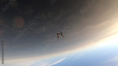Freefly skydiving. Two guys are flying headdown in the sunset sky. Slow motion.