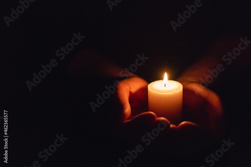 Hands holding burning candle in dark like a heart.Selective focus,black background.Copy space. photo