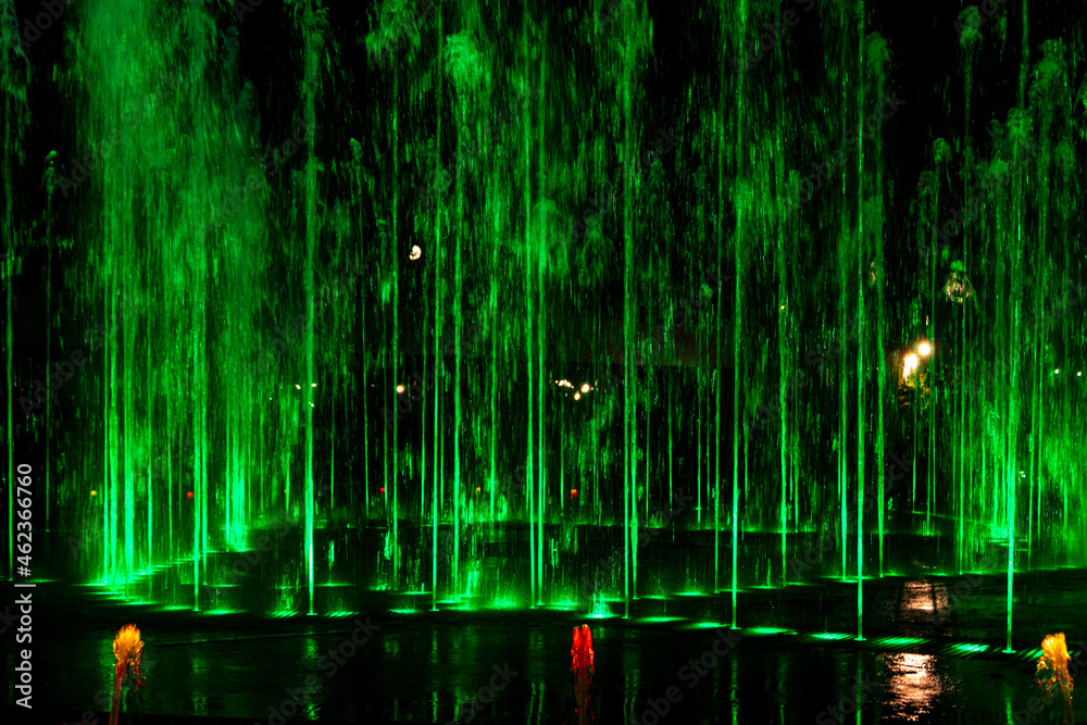 Green jets of the fountain at night.