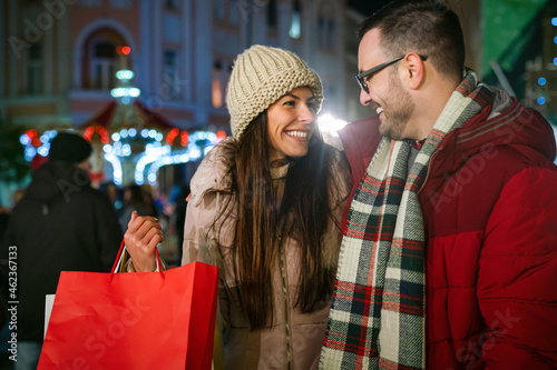 Romantic Christmas shopping. Happy young couple buying gifts for family. Sale and people concept.