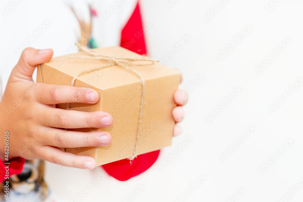 Young boy hands in pullover holding Christmas gift box on gray background.Christmas and New Year banner.Copy space. Young boy hands in pullover holding Christmas gift box on gray background.Christmas and New Year banner.Copy space.