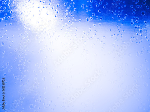 Close-up, water droplets on frosted glass shower room or window, door, white light reflected from inside, blue wall, Thailand.