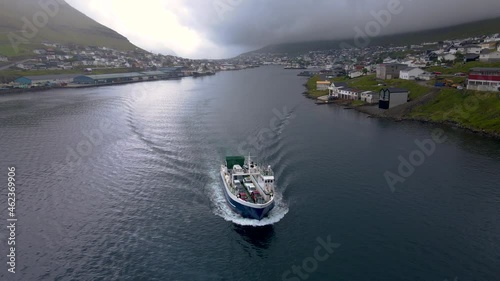 Beautiful aerial view of the City of Klaksvik in the Fareo Islands with the ferry full of cars, surrounded by colorful houses and the amazing canal and view to the majestic Kunoy Park