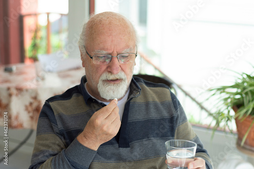  bald old man with glasses taking his daily meds. Selective Focus Man