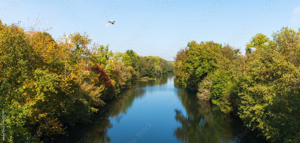 Autumn in French countryside. Loing river canal in Ile-de-France, France. Beautiful reflection of autumn trees and blue sky water. Nature seasonal landscape background. Selective focus on reflection.