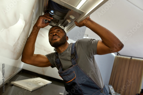 Fotografi Handsome workman checking kitchen exhaust filters with flashlight