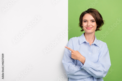 Photo of nice cool young happy woman point finger empty space board advert isolated on green color background