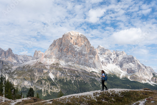 Hiker woman with backpack in front of limestone mountain of Tofana di Rozes, Italy. Adventurous concept.