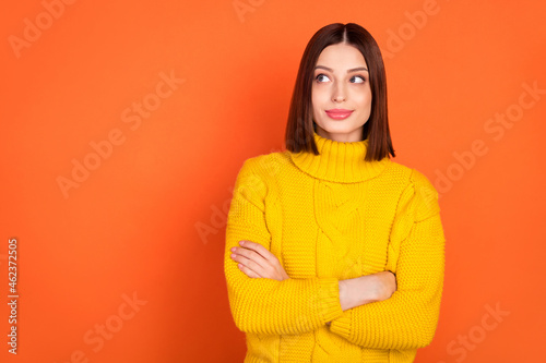 Photo of young attractive woman happy positive smile folded hands think look empty space isolated over orange color background © deagreez