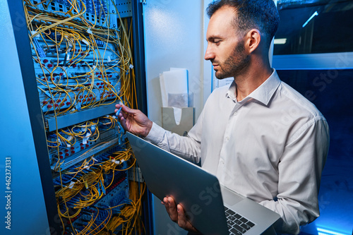 Foto Male IT engineer connecting cable to server rack