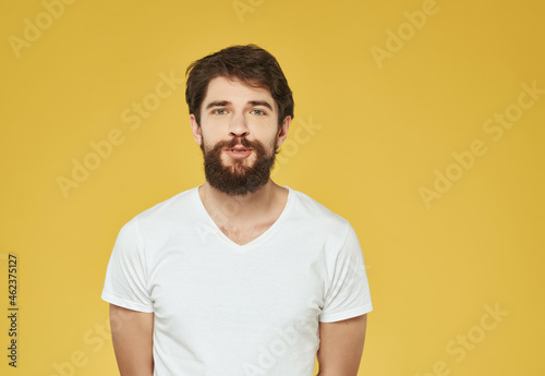 emotional man in a white t-shirt hand gestures anger yellow background