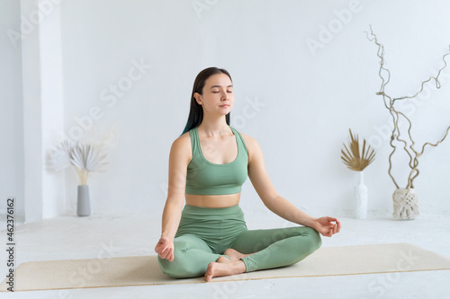 Young woman practices yoga in the lotus position. Cross-legged pose. photo