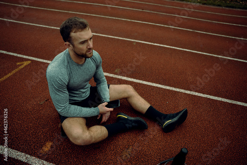 Caucasian male athlete sitting on track field 