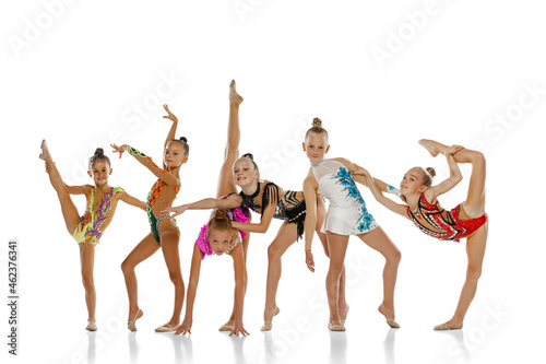 Studio shot of group of mixed-ages beautiful rhythmic gymnastics artists, girls posing isolated on white studio background.