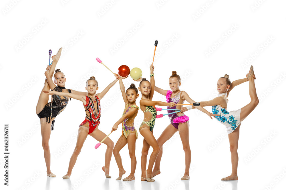 Group of little beautiful rhythmic gymnastics artists, girls posing isolated on white studio background. Concept of sport, action, team, show