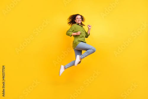 Photo of beautiful funky funny positive stylish woman dressed green shirt jumping high running smiling isolated yellow color background