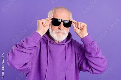 Portrait of attractive content serious grey-haired man touching specs modern look isolated over bright violet purple color background